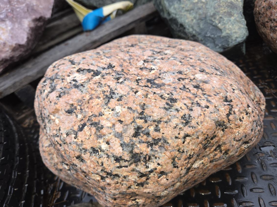Close view of a pink and black speckled hand cut Italian granite stone