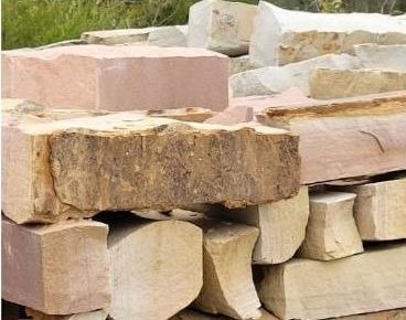 Roughly cut rectangular stone slabs stacked in tan, grey and brown